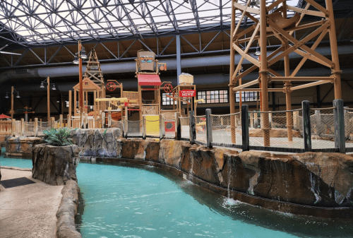 Indoor water park featuring a lazy river, rock formations, and a play structure with slides and water features.