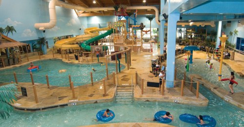 Indoor water park featuring slides, a lazy river, and various pools with people enjoying the attractions.