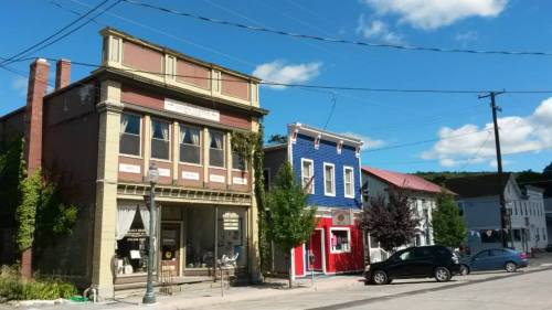 A quaint street scene featuring colorful storefronts and a clear blue sky with fluffy clouds.