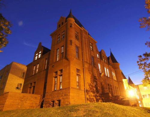 Historic building illuminated at night, featuring ornate architecture and a dark blue sky in the background.