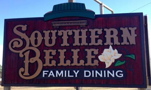 Sign for "Southern Belle Family Dining" featuring a magnolia flower and a decorative design.