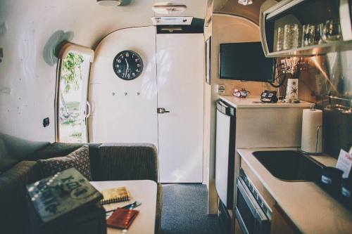 Interior of a cozy camper with a clock, kitchenette, and seating area, featuring warm lighting and a welcoming atmosphere.