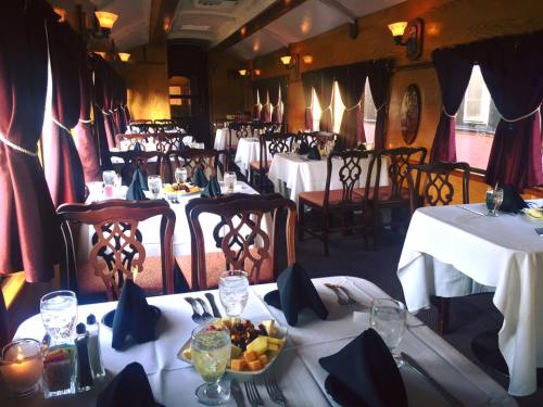 Elegant dining area with white tablecloths, dark wood chairs, and large windows, set for a meal with fruit plates.