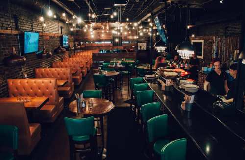A stylish restaurant interior with cozy booths, a bar, and warm lighting, creating an inviting atmosphere.