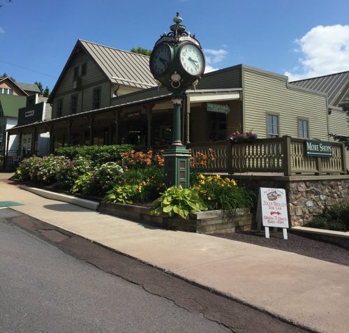 A charming building with a clock tower, surrounded by colorful flowers and greenery, on a sunny day.