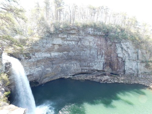 A scenic waterfall cascading into a serene pool, surrounded by rocky cliffs and lush greenery.