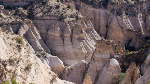 A rugged landscape of layered rock formations and steep cliffs in a desert setting.