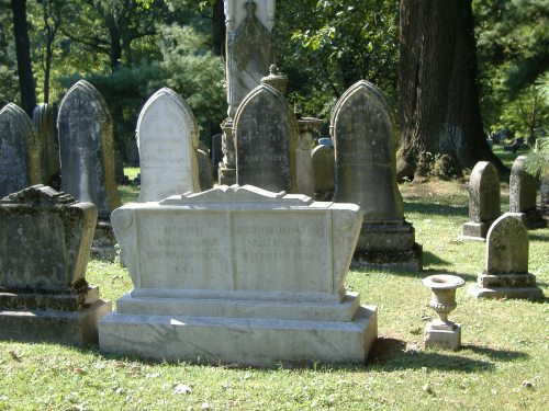 A cemetery scene featuring several old gravestones and a large, ornate tombstone in the foreground.