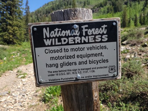 Sign indicating the National Forest Wilderness area is closed to motor vehicles, motorized equipment, hang gliders, and bicycles.