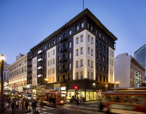 Historic building at dusk, featuring a mix of architectural styles, with bustling street activity and city lights.