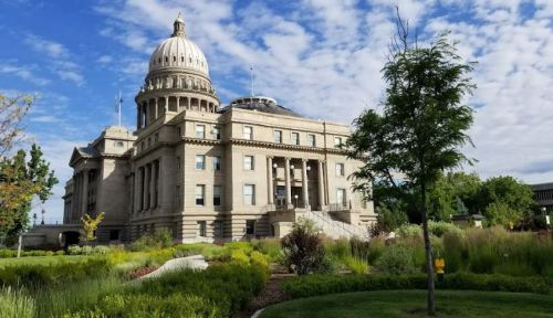 Historic building with a dome, surrounded by greenery and blue skies, showcasing a beautiful landscape.