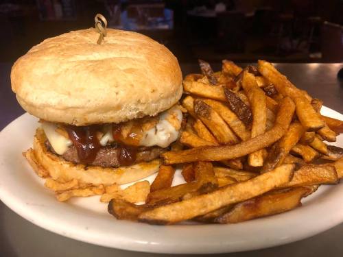 A juicy burger with melted cheese and barbecue sauce, served with a side of crispy golden fries.