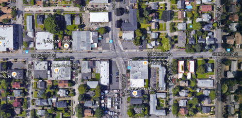 Aerial view of a city intersection with buildings, streets, and nearby residential areas.