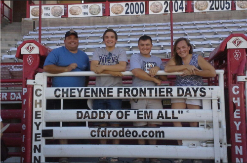 A family poses together at Cheyenne Frontier Days, smiling in front of a rodeo sign.