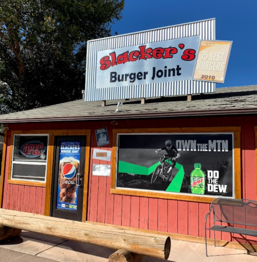 A small burger joint with a sign reading "Slacker's Burger Joint" and a large advertisement for Mountain Dew.