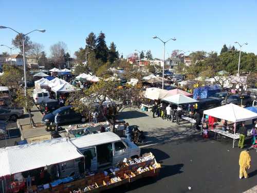 A bustling outdoor market with numerous tents, vendors, and shoppers under a clear blue sky.