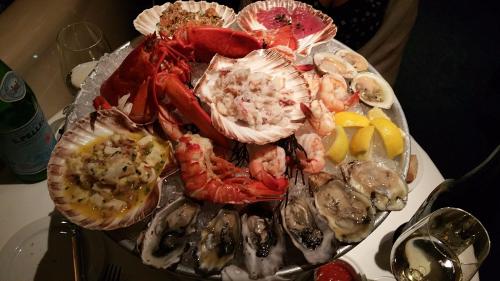 A seafood platter featuring lobster, shrimp, oysters, and scallops on ice, garnished with lemon wedges.