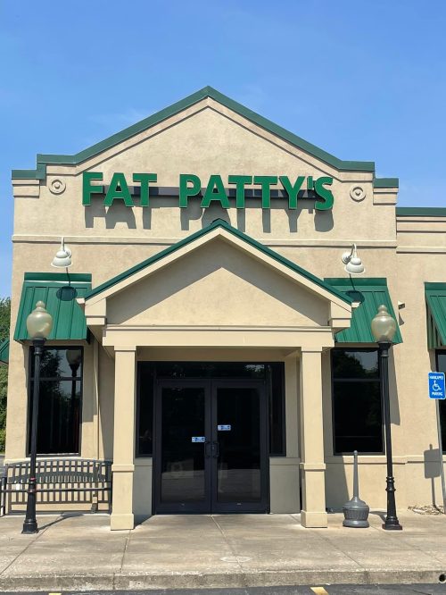 Exterior of Fat Patty's restaurant, featuring a green sign and a welcoming entrance under a clear blue sky.
