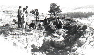 A group of people examining a rocky excavation site in a mountainous area.