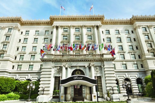 Exterior of the Fairmont Hotel, featuring a grand entrance and multiple international flags displayed.