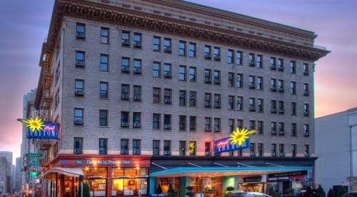 Historic hotel building with neon signs, street view at dusk, showcasing architectural details and vibrant colors.