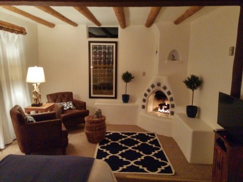 Cozy room with a fireplace, two chairs, a lamp, and a decorative rug, featuring warm lighting and a welcoming atmosphere.