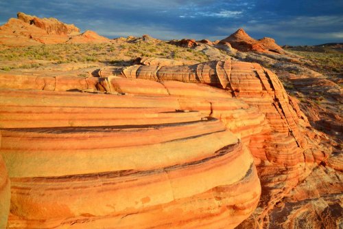 Colorful rock formations with layered textures under a blue sky, showcasing natural erosion and desert landscape.