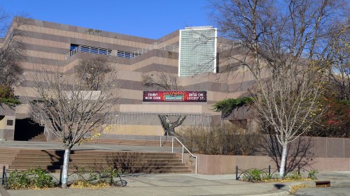 Modern building with a zigzag design, featuring trees and a clear blue sky in the background.