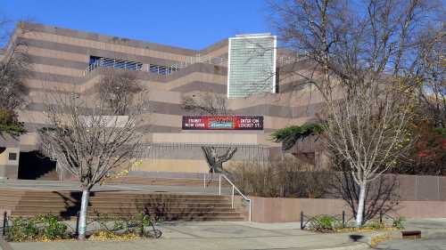 Modern building with a zigzag design, featuring trees and a clear blue sky in the background.