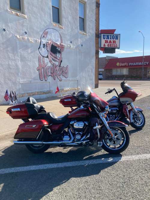 Two red motorcycles parked in front of a mural featuring a football player, near a bar and grill.