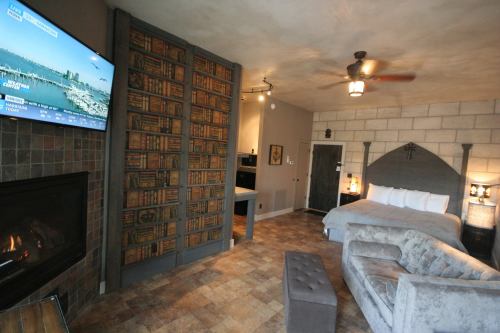 Cozy hotel room featuring a king bed, fireplace, TV, and a bookshelf accent wall. Modern decor with warm tones.