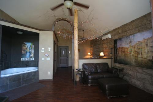 Cozy living space with a leather couch, decorative wall art, and a bathroom area featuring a tub and soft lighting.