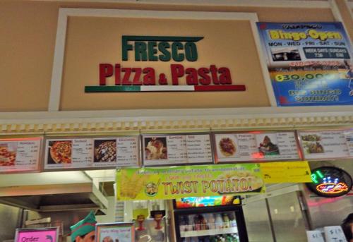 Sign for "Fresco Pizza & Pasta" with menu items displayed below, featuring various food options.