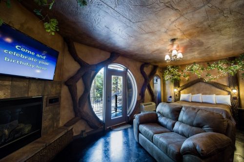 Cozy room with a round window, fireplace, and a bed, decorated with greenery and a TV inviting birthday celebrations.