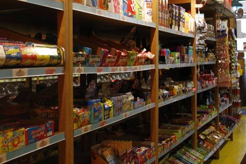 A colorful display of various candy and snack items on wooden shelves in a store.
