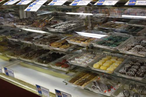 A display case filled with various types of cookies and chocolates, neatly arranged on trays.