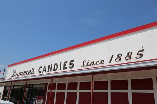 Sign for Lamme's Candies, established in 1885, on a bright blue sky day.