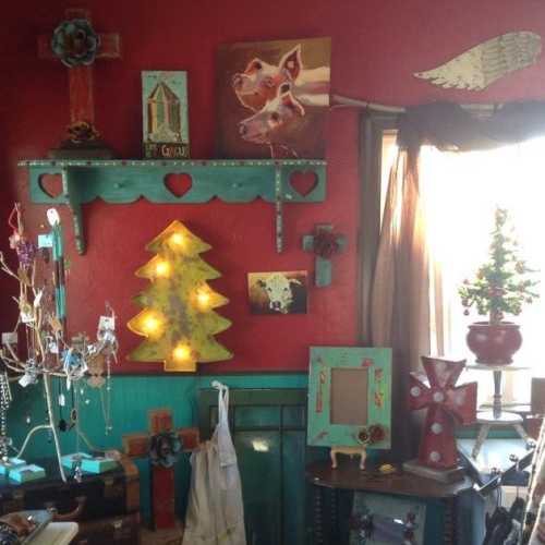 Colorful interior decor featuring a red wall, eclectic art, and unique ornaments, including a tree and a cross.