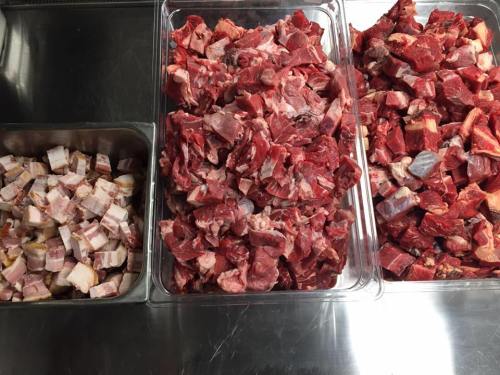 Three containers of raw meat: one with cubed fat, and two with various cuts of red meat.