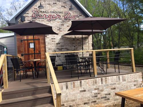 A brick building with a sign reading "Burger Bis," featuring outdoor seating under umbrellas on a wooden deck.