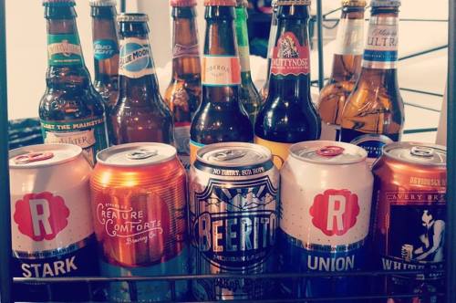 A variety of beer bottles and cans arranged on a shelf, featuring different brands and styles.