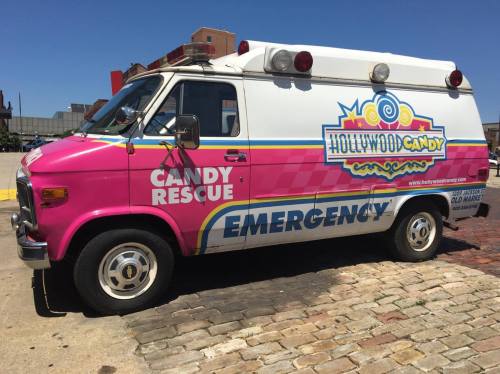 A colorful candy-themed van with "Candy Rescue" and "Emergency" written on the side, parked on a cobblestone street.