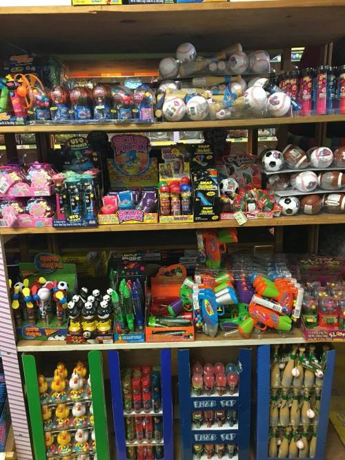 A colorful display of various toys and games on wooden shelves, including balls, water guns, and novelty items.