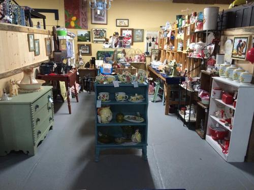 A cozy thrift shop interior filled with various vintage items, shelves, and displays of dishes and home decor.