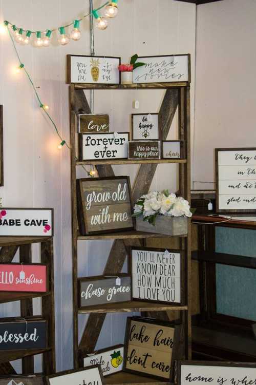 A wooden display shelf with various decorative signs and a bouquet of flowers, set in a cozy, well-lit space.