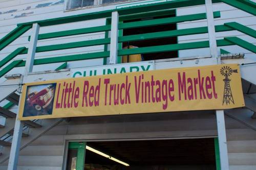 Sign for "Little Red Truck Vintage Market" with a vintage truck image and a windmill graphic. Green and yellow colors.