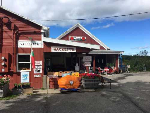 A red barn-style building with signs for a salesroom and apple crisp, featuring a large pumpkin outside.