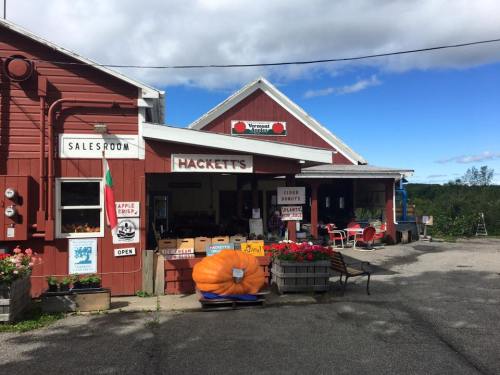 A red barn-style building with signs for a salesroom and apple crisp, featuring a large pumpkin outside.