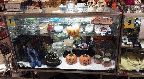 Display case filled with various decorative items, including shoes, glassware, and Halloween-themed decorations.