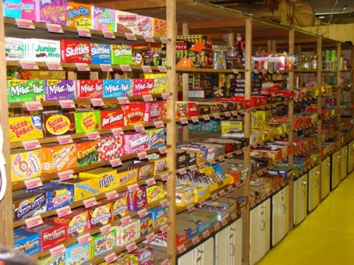 A colorful display of various candy and snacks on wooden shelves in a store.